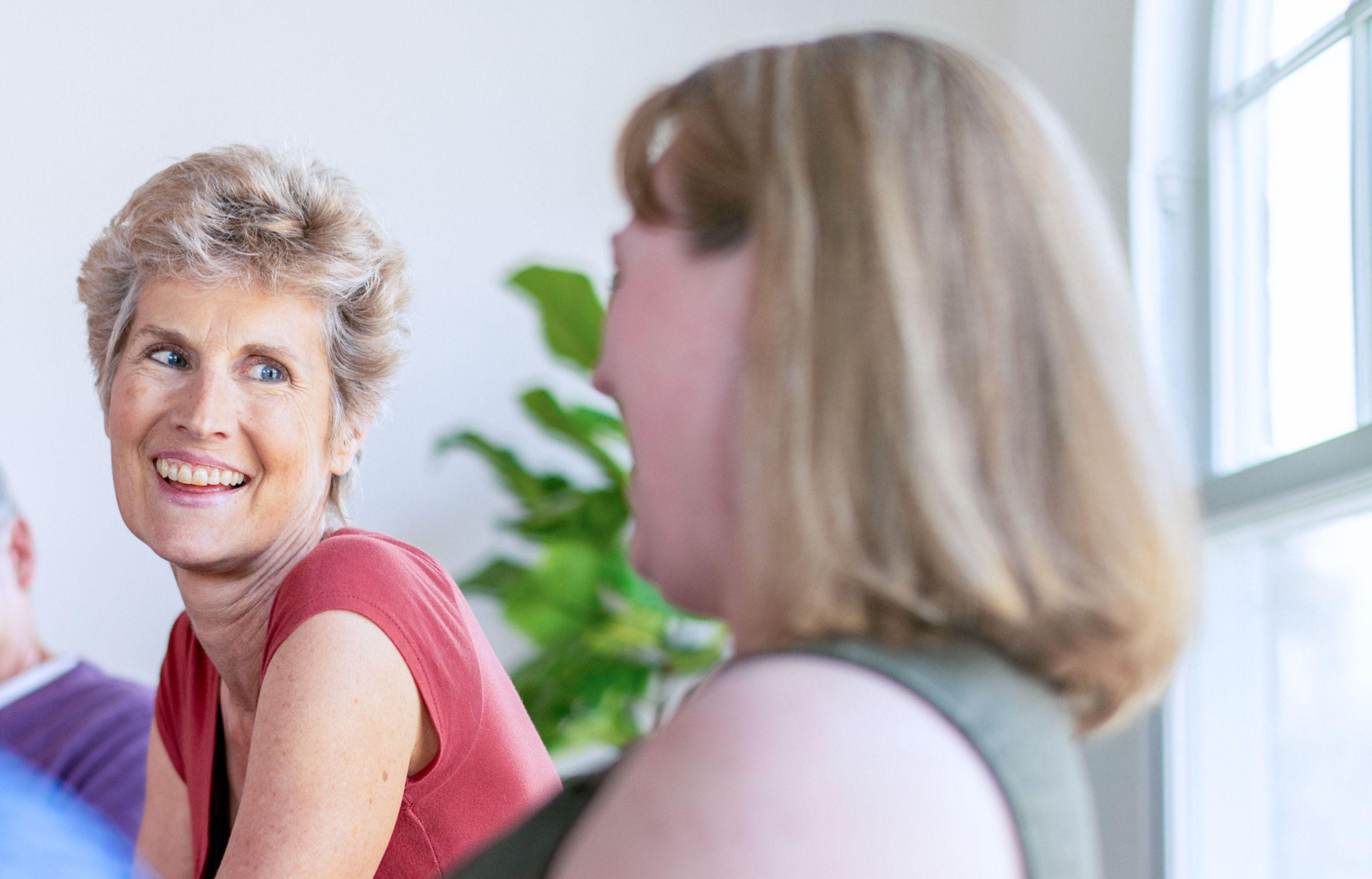 Smiling middle-aged white woman chatting with coworkers in an office